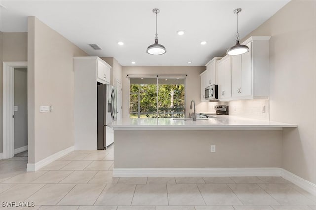 kitchen featuring pendant lighting, white cabinets, stainless steel appliances, sink, and kitchen peninsula