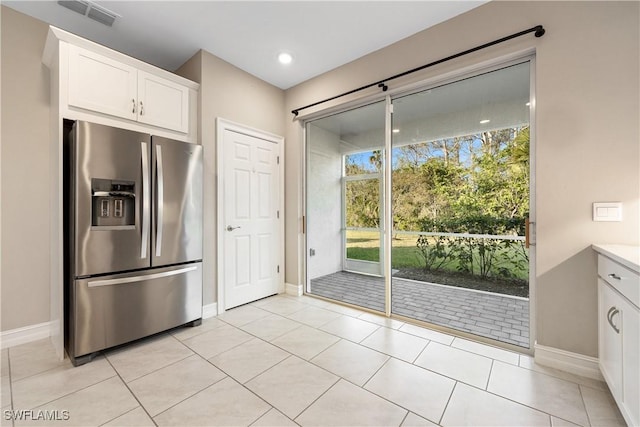 kitchen with light tile patterned floors, stainless steel fridge with ice dispenser, and white cabinetry