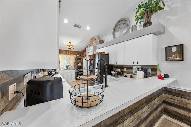 kitchen featuring white cabinets, stainless steel fridge with ice dispenser, and vaulted ceiling