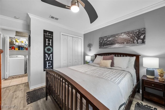 bedroom with washer and clothes dryer, ceiling fan, crown molding, wood-type flooring, and a closet