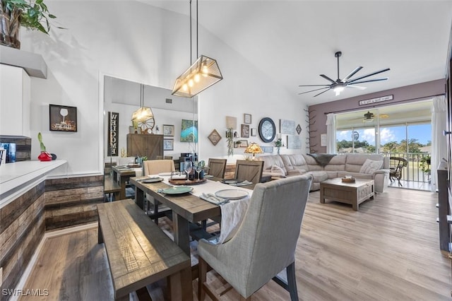 dining space with high vaulted ceiling, light hardwood / wood-style flooring, and ceiling fan