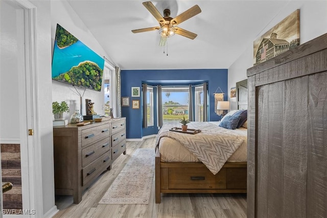 bedroom with ceiling fan, light hardwood / wood-style floors, and vaulted ceiling