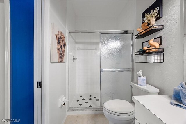 bathroom featuring tile patterned floors, a shower with door, and toilet