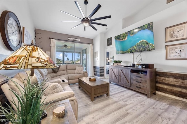 living room with ceiling fan, lofted ceiling, and light wood-type flooring