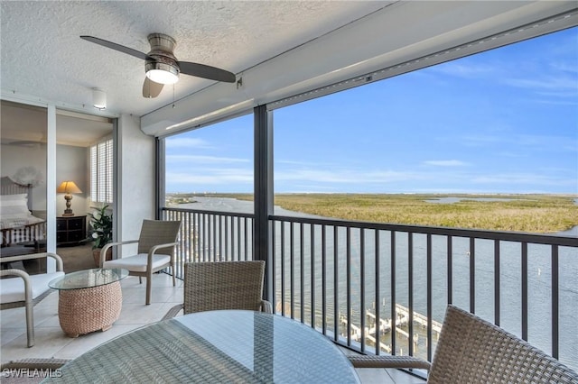 balcony with ceiling fan and a water view