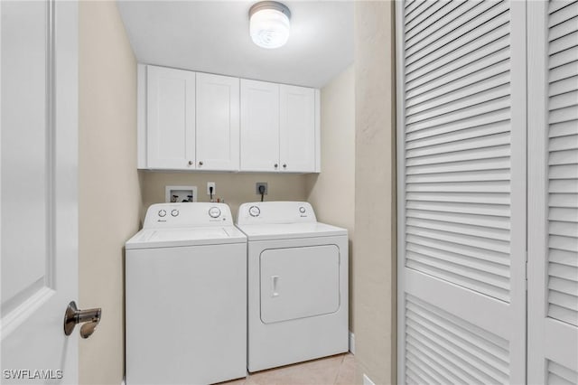 laundry room with cabinet space, light tile patterned floors, and washer and clothes dryer