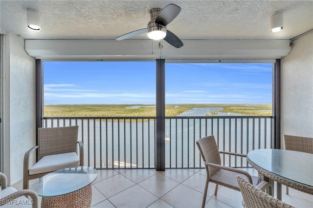 sunroom with a water view and ceiling fan