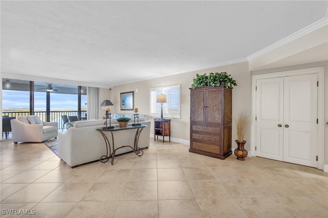 living room featuring baseboards, a ceiling fan, expansive windows, crown molding, and light tile patterned flooring