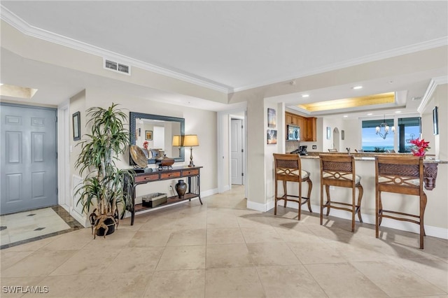 kitchen with a tray ceiling, visible vents, stainless steel microwave, a peninsula, and a kitchen breakfast bar