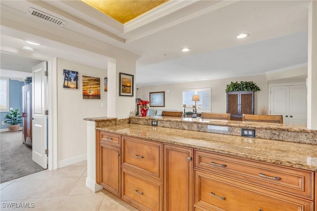 kitchen with light tile patterned floors, light stone counters, brown cabinetry, and visible vents