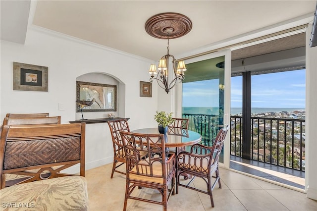 dining room featuring a wall of windows, a water view, an inviting chandelier, and crown molding