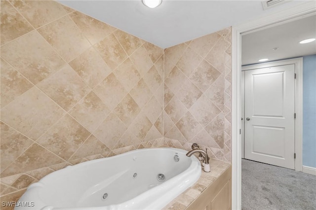 bathroom with a tub with jets and recessed lighting