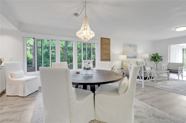 dining room featuring a healthy amount of sunlight, light wood-type flooring, and an inviting chandelier