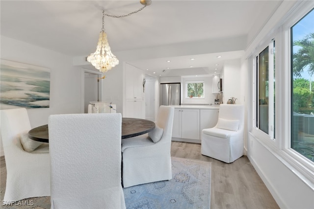 dining space featuring light wood-type flooring, a wealth of natural light, and a chandelier