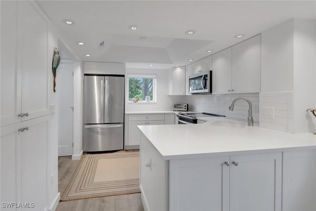 kitchen with kitchen peninsula, white cabinetry, and appliances with stainless steel finishes