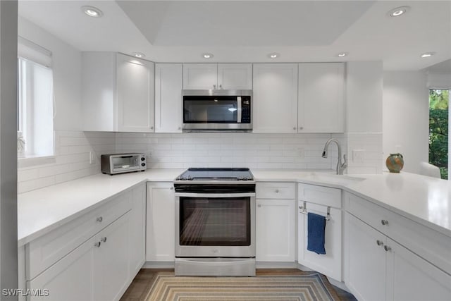 kitchen with backsplash, white cabinetry, sink, and appliances with stainless steel finishes