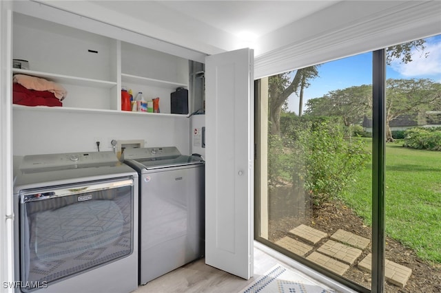 laundry area with washing machine and clothes dryer and light hardwood / wood-style floors