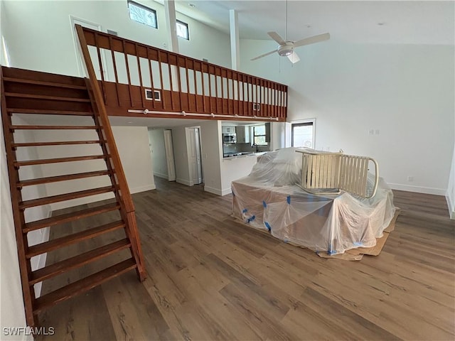 living room with hardwood / wood-style floors, ceiling fan, and a high ceiling