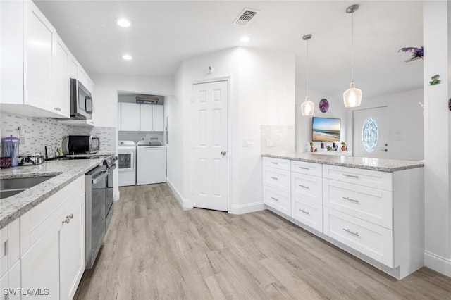 kitchen featuring appliances with stainless steel finishes, backsplash, separate washer and dryer, white cabinets, and hanging light fixtures