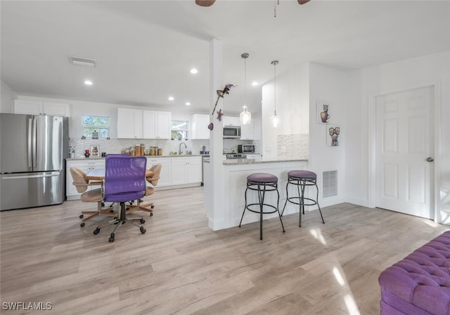 kitchen with white cabinets, light wood-type flooring, stainless steel appliances, and kitchen peninsula