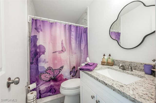 bathroom with curtained shower, vanity, and toilet