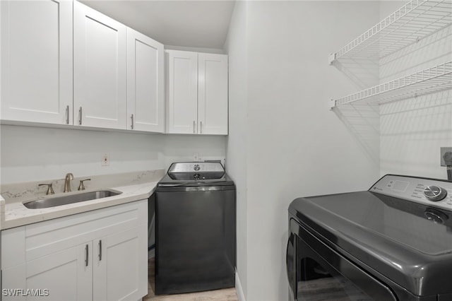 laundry area featuring washer and clothes dryer, cabinets, and sink