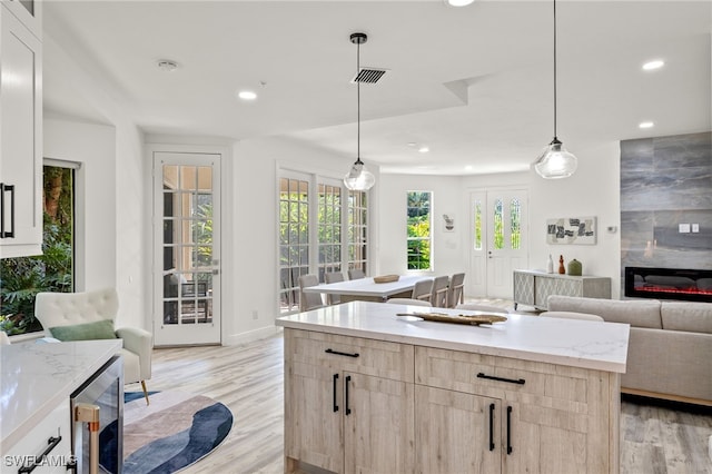 kitchen with pendant lighting, a center island, light hardwood / wood-style flooring, a fireplace, and beverage cooler