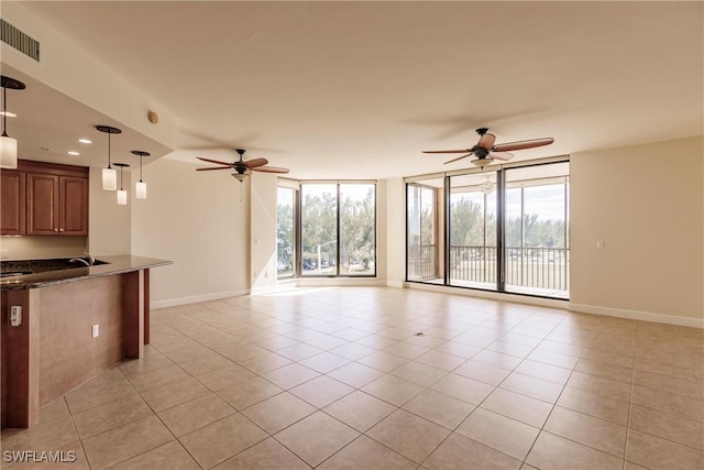 unfurnished living room featuring ceiling fan, a wall of windows, and light tile patterned floors