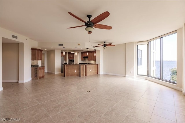 unfurnished living room featuring plenty of natural light, expansive windows, a water view, and ceiling fan