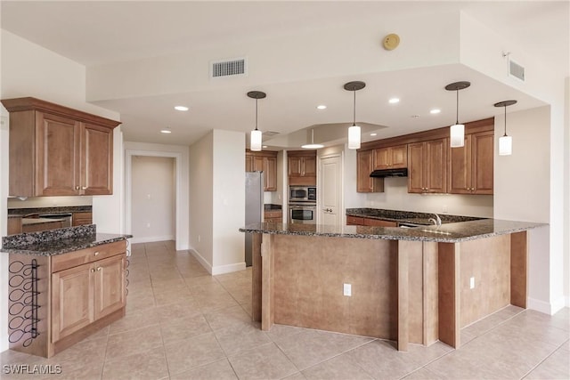 kitchen featuring pendant lighting, kitchen peninsula, dark stone countertops, and stainless steel appliances