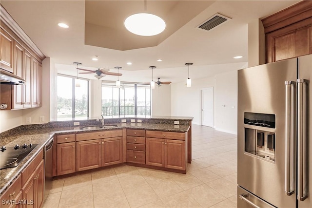 kitchen featuring a raised ceiling, sink, hanging light fixtures, kitchen peninsula, and stainless steel appliances