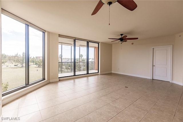 unfurnished room featuring ceiling fan, light tile patterned flooring, and a wall of windows