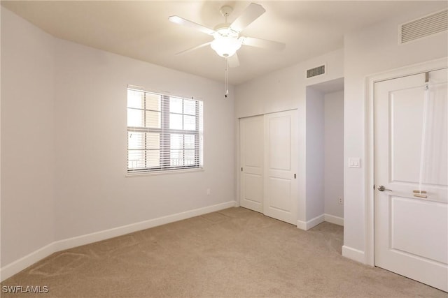 unfurnished bedroom featuring light carpet, a closet, and ceiling fan