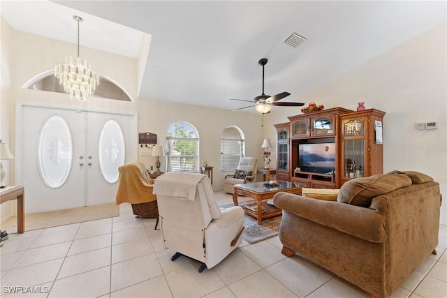 tiled living room featuring ceiling fan with notable chandelier and french doors