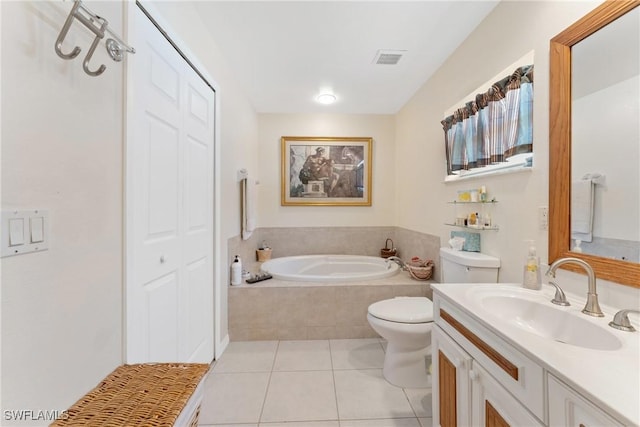 bathroom featuring tile patterned floors, tiled tub, vanity, and toilet