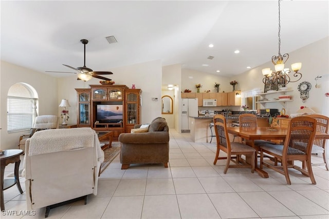 dining area with ceiling fan with notable chandelier, light tile patterned floors, and vaulted ceiling