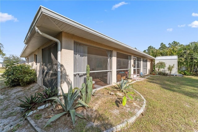 view of side of home featuring a sunroom and a yard