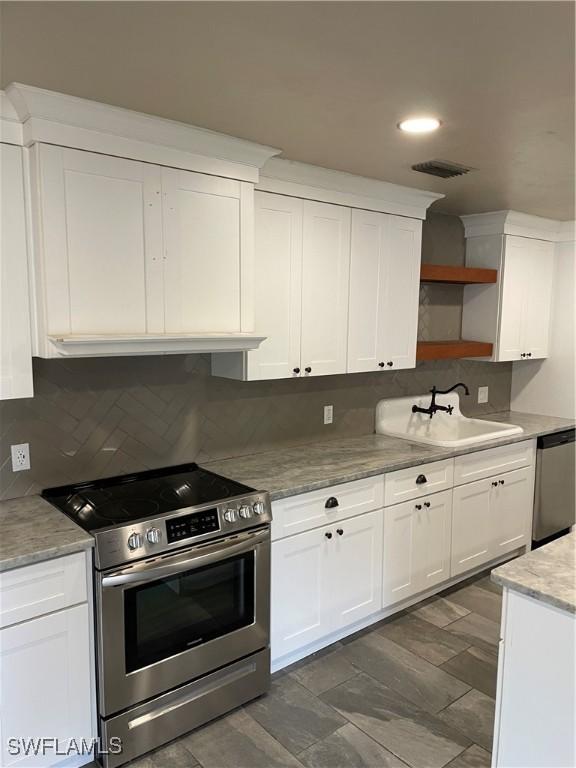 kitchen with light stone countertops, tasteful backsplash, stainless steel appliances, sink, and white cabinetry