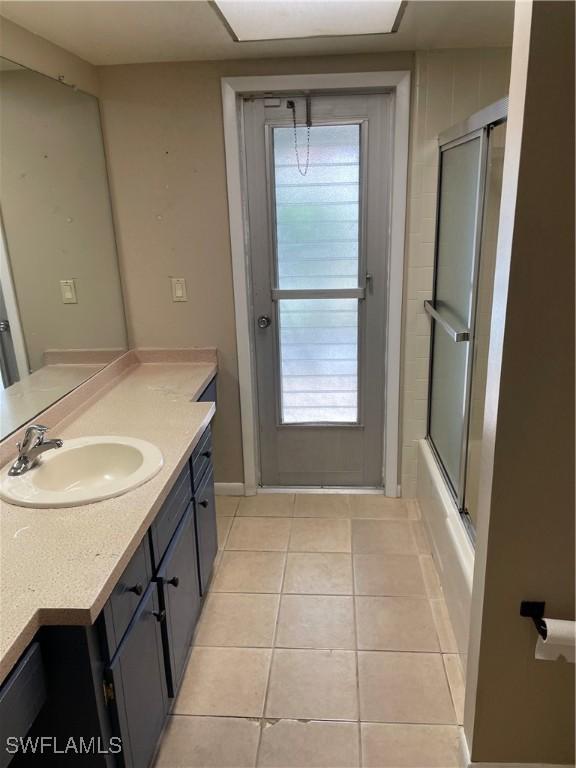 bathroom featuring tile patterned floors, vanity, and enclosed tub / shower combo