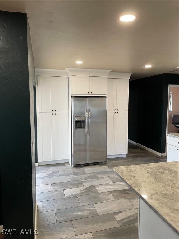 kitchen with white cabinets, stainless steel fridge, and light stone countertops