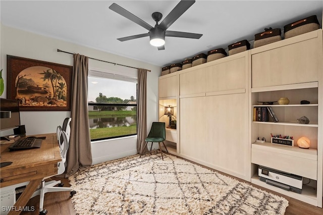 office area with hardwood / wood-style floors, ceiling fan, and a water view