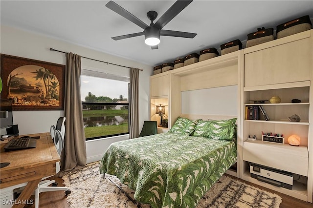 bedroom with ceiling fan, hardwood / wood-style floors, and a water view