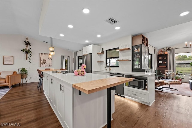 kitchen with white cabinets, stainless steel appliances, lofted ceiling, and a kitchen island