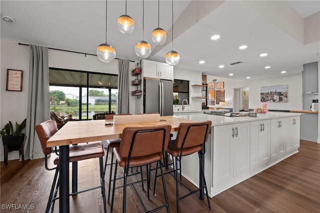 kitchen with white cabinetry, a center island, sink, hanging light fixtures, and stainless steel fridge