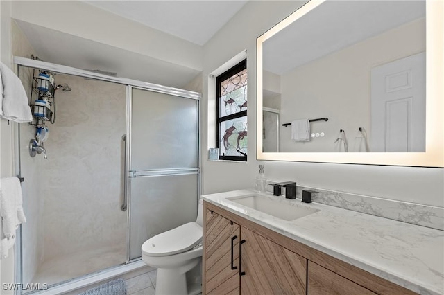 bathroom featuring toilet, vanity, tile patterned floors, and a shower with door