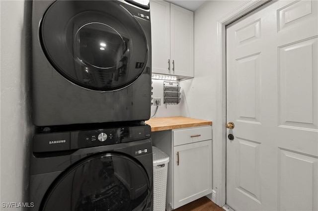 washroom with cabinets and stacked washer / drying machine