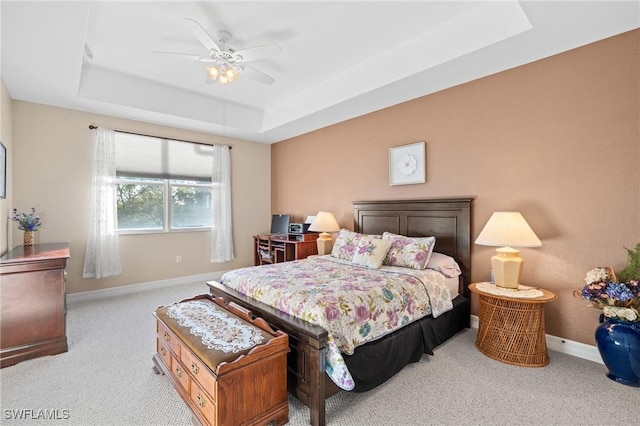 carpeted bedroom with ceiling fan and a tray ceiling