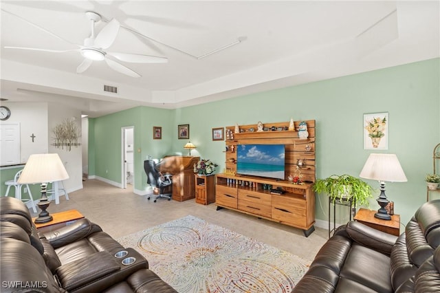 living room with ceiling fan and a tray ceiling