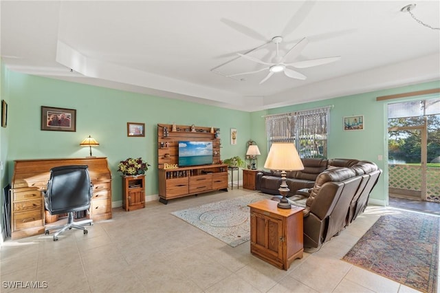 living room with a tray ceiling and ceiling fan