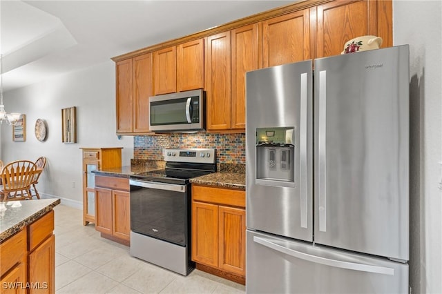 kitchen with an inviting chandelier, light tile patterned floors, dark stone countertops, stainless steel appliances, and backsplash